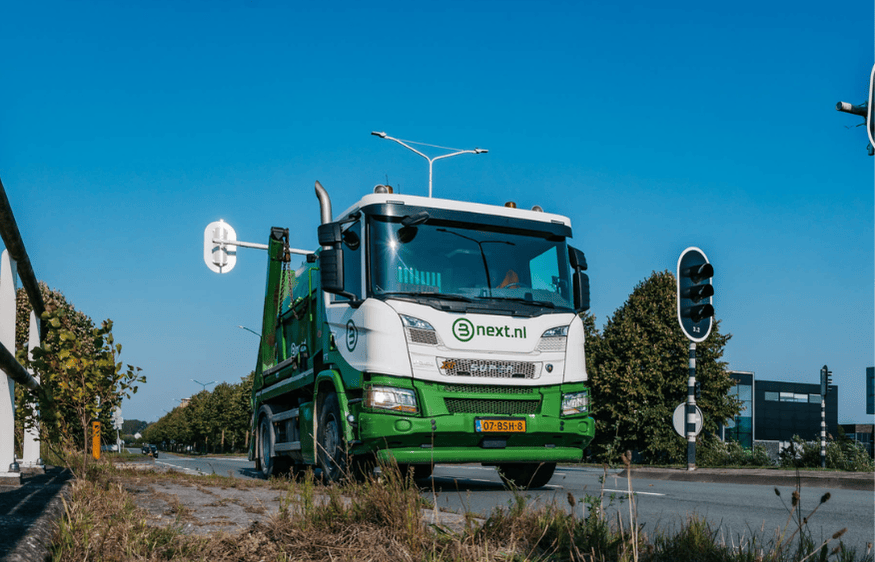 Vrachtwagen rijdt op een weg met een 9m3 gesloten afvalcontainer